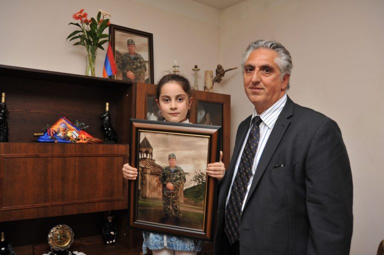 Volunteer Suren Djaratanyan's granddaughter poses with a photo of her Hero grandfather.