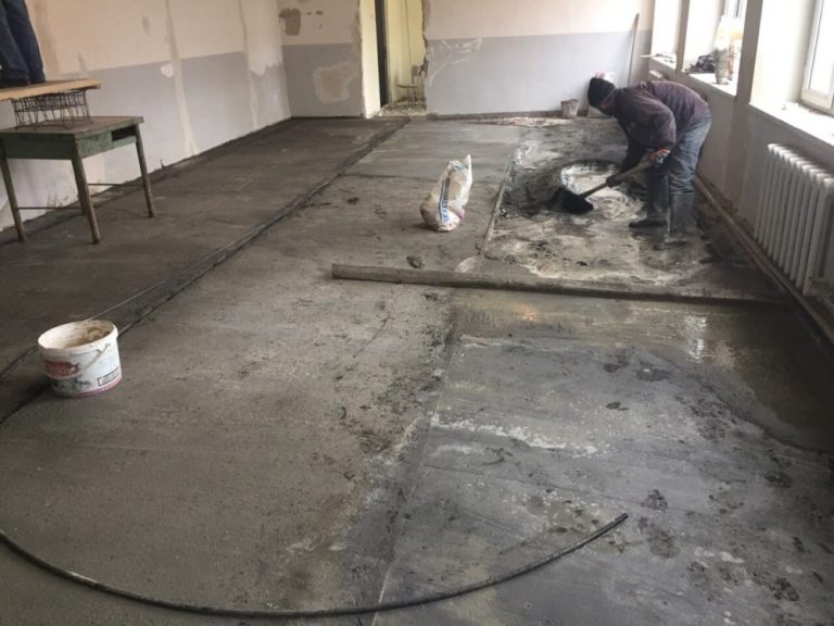 Member of the renovation crew pouring the subfloor in the kitchen and cafeteria area.