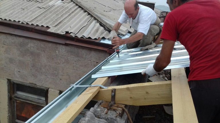 Each piece of metal roofing is screwed into place to ensure strength against the wind and other elements.  New downspouts were also installed.