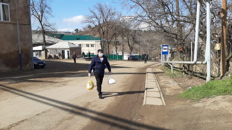 Municipal workers and volunteers help distribute food packs to the elderly in the City of Berd.