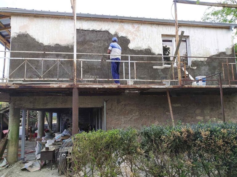 Work on the exterior of Emma's home continues.  New stucco hides the scares of war.