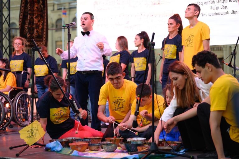 Kharpert residents performing a percussion piece in the background as the other participants take the stage singing.